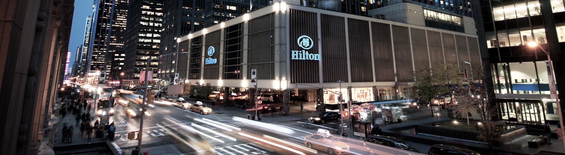 Flagship Hilton hotel in times square at night time with traffic on street 
